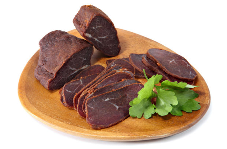 Basturma, dried tenderloin of beef meat, thinly sliced, on a flat wooden dish, Isolated on white background.